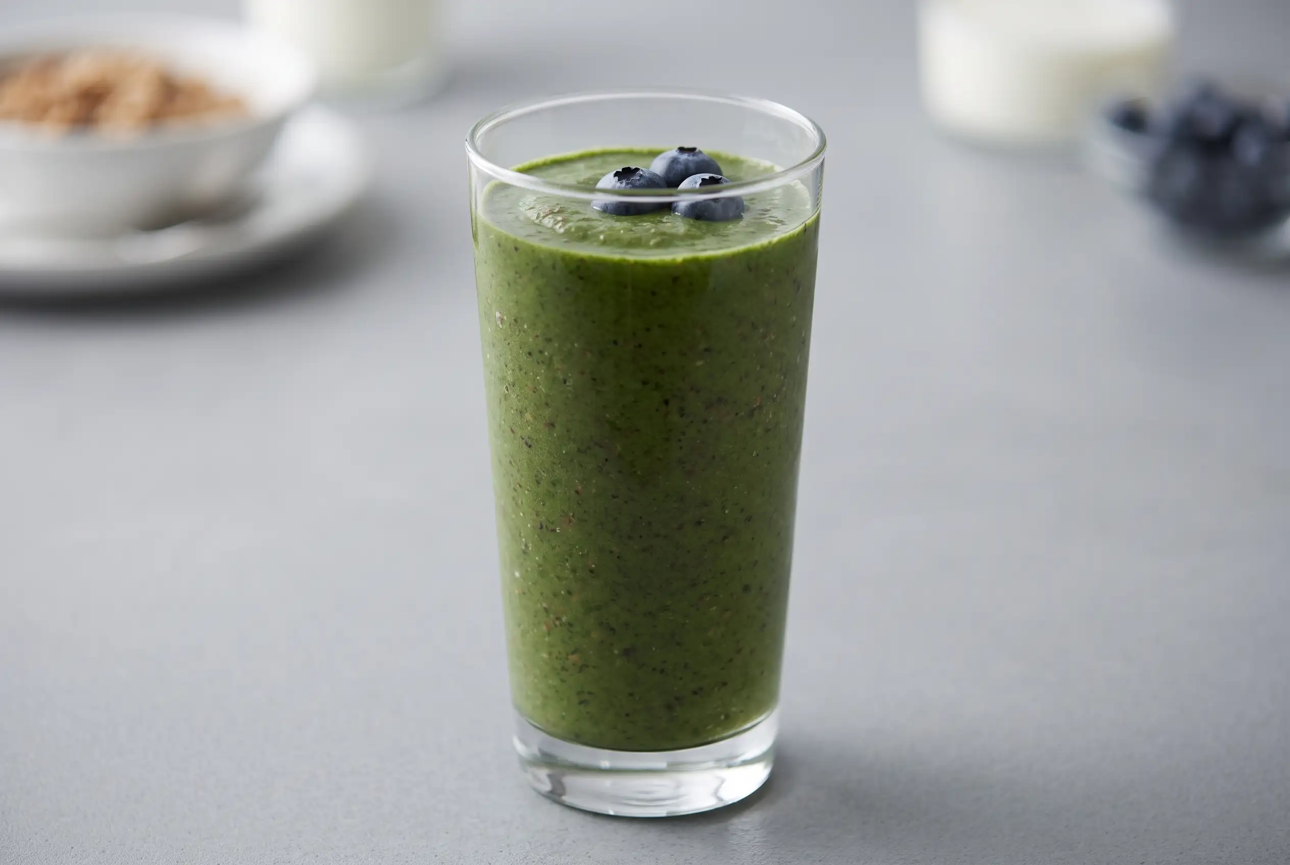 Berry Green Smoothie with Bran Cereal Berry green smoothie with berries and bran cereal in a tall glass for breakfast