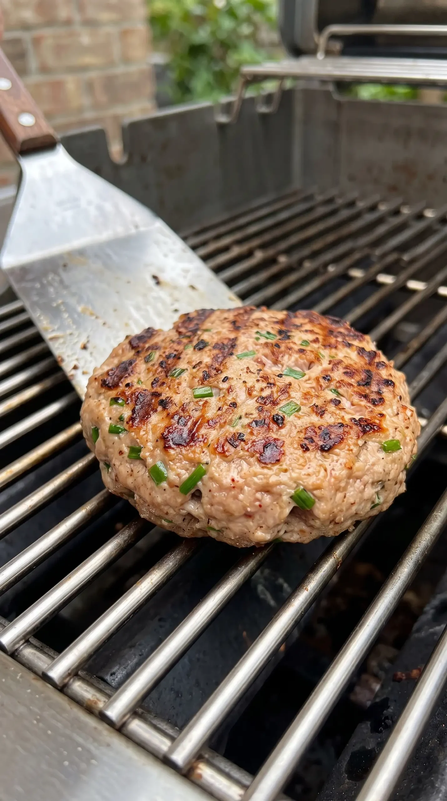Seasoned turkey burger patty grilling with browning developing on the surface