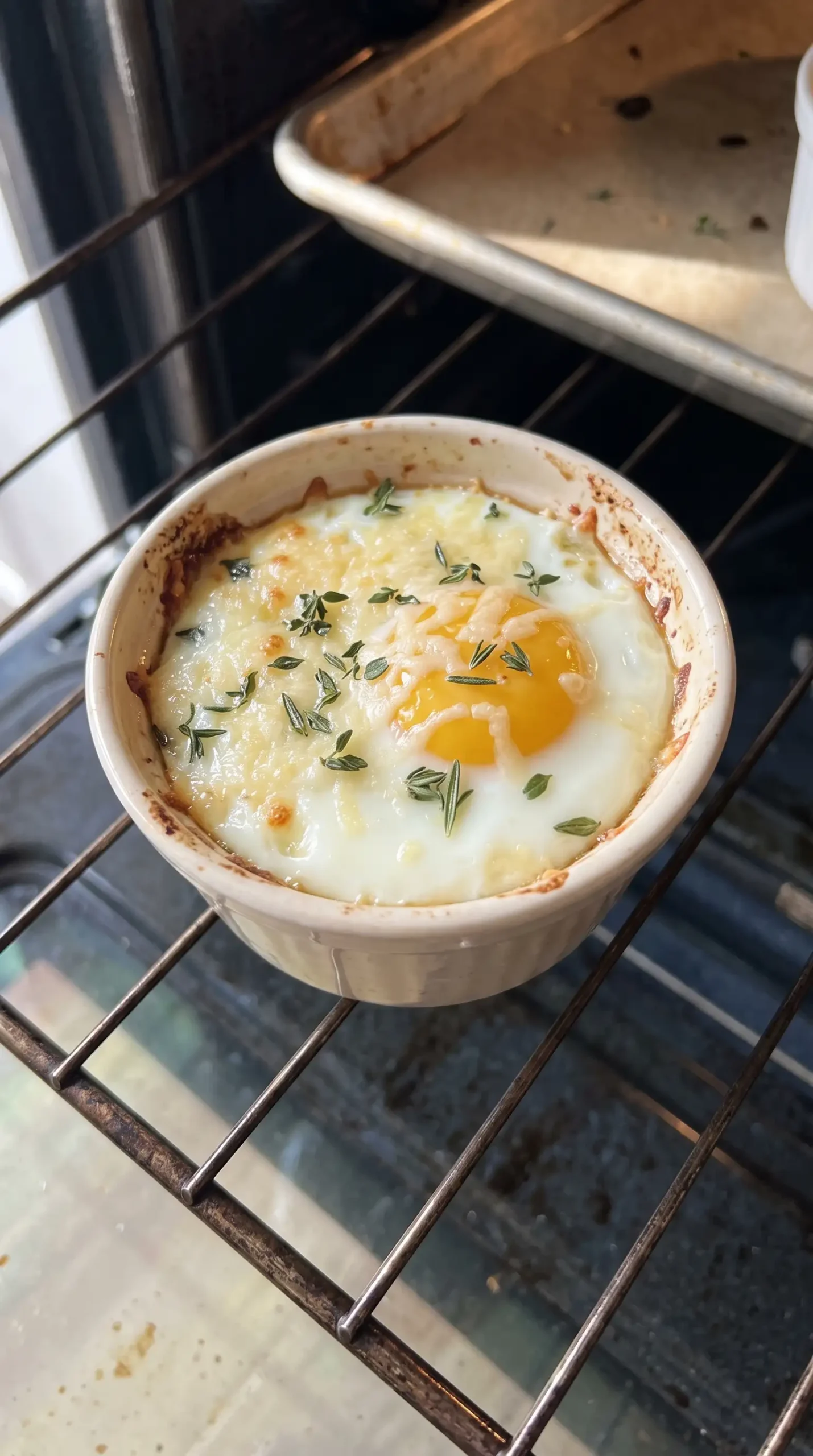 Baked eggs with parmesan in a ramekin during the oven finishing stage