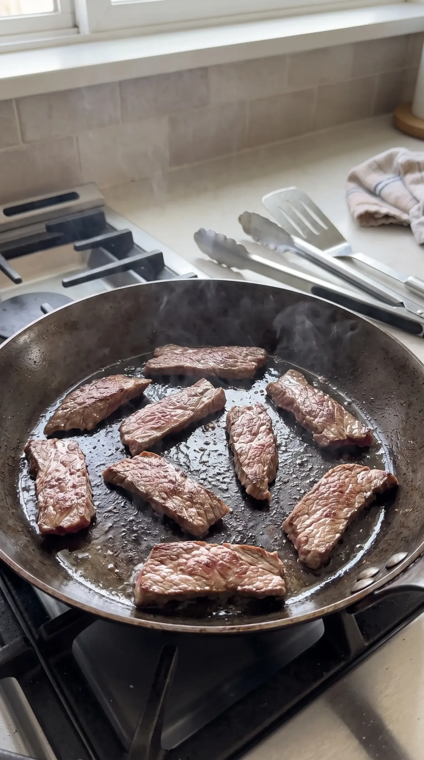Thinly sliced flank steak searing in a hot skillet before making orange beef stir-fry