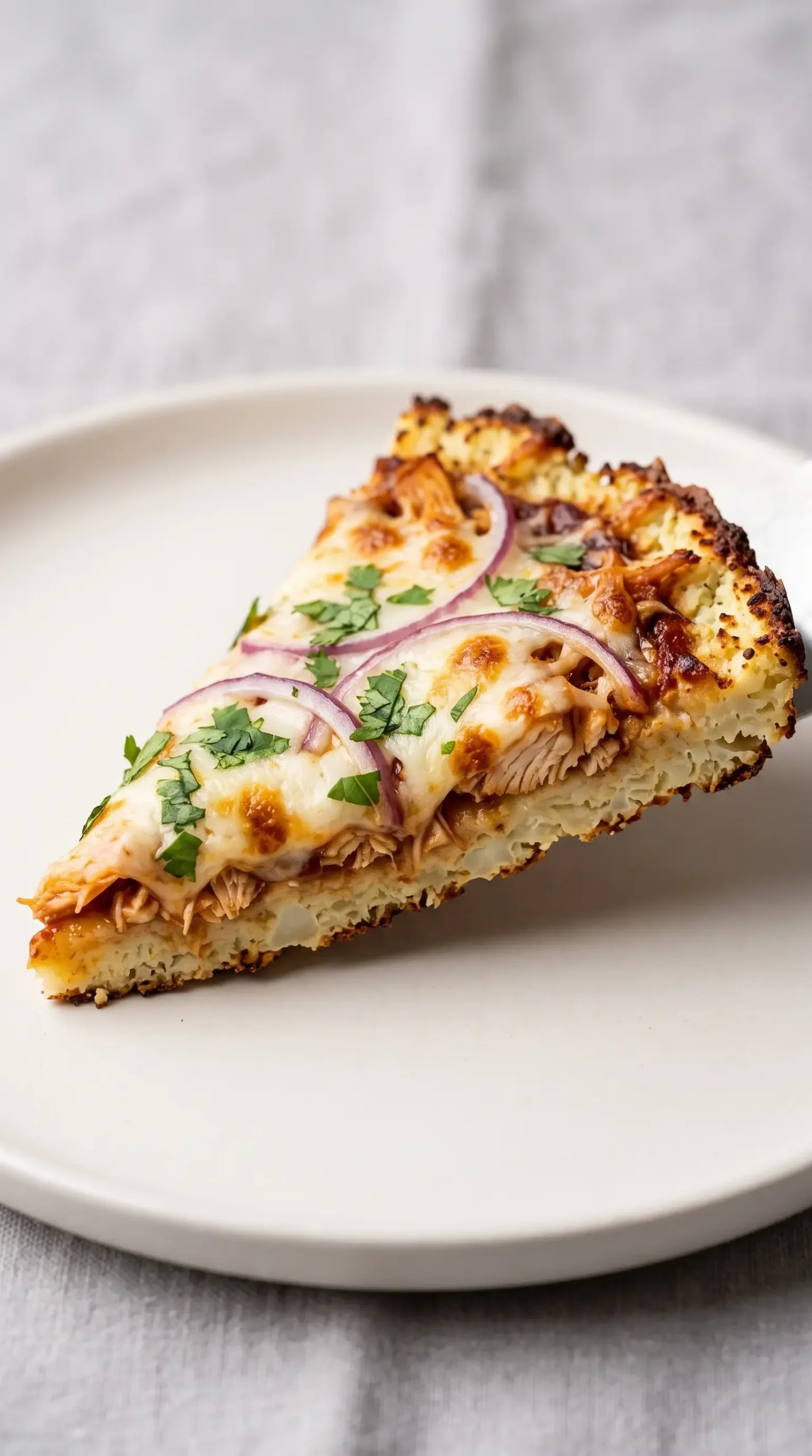 Served BBQ chicken cauliflower pizza slice showing crisp crust and melted cheese