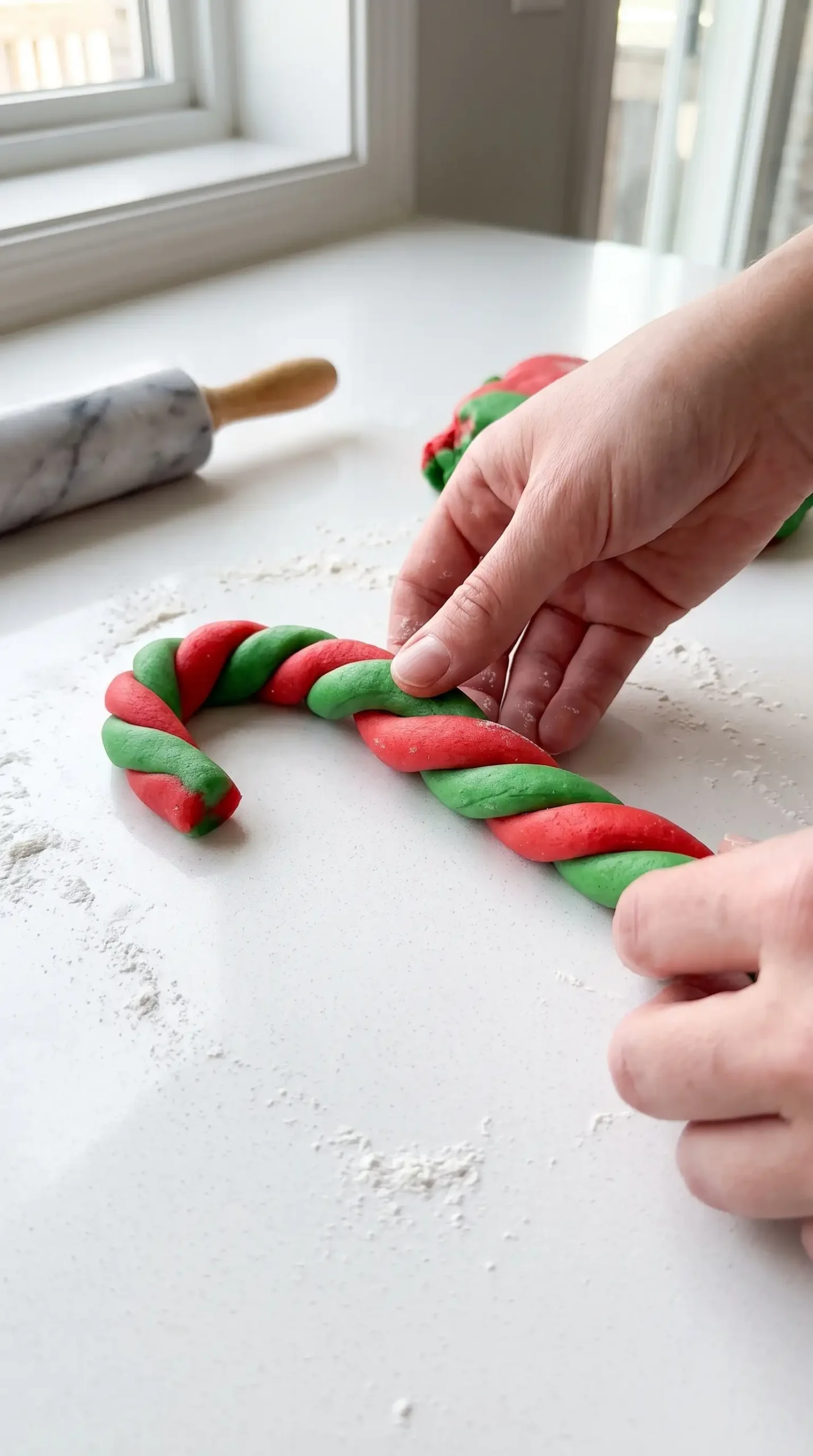 Red and green cookie dough ropes twisted into candy cane shapes